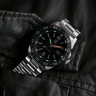 Silver watch with black dial on a dark fabric background