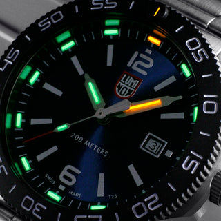 Close-up of a watch face with green glowing elements and a brand logo.